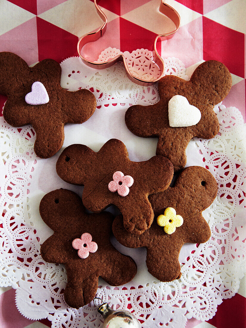 Gingerbread men with icing and cookie cutters on a red and white tablecloth