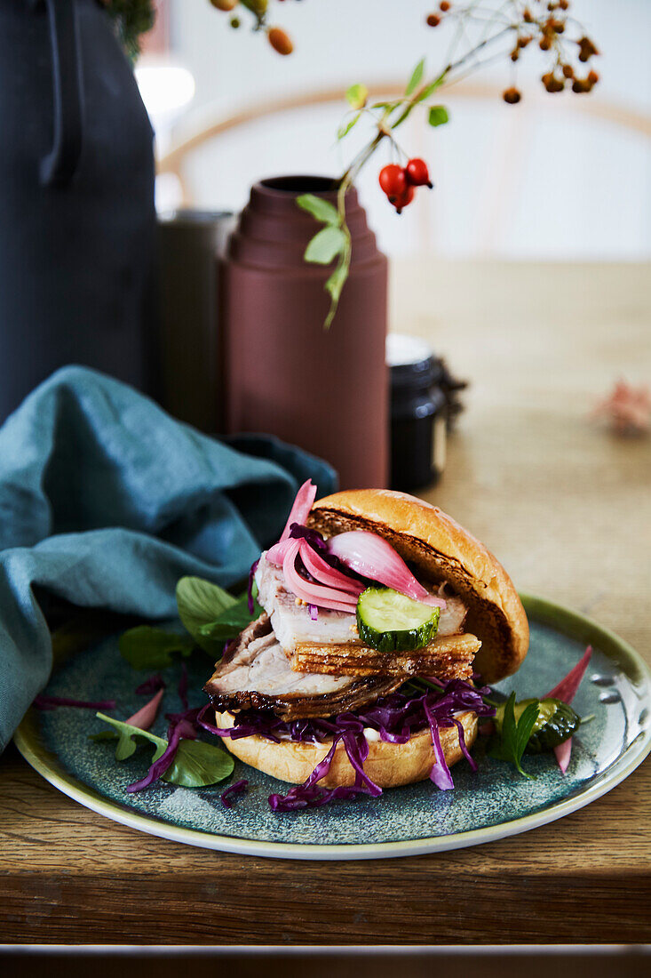 Burger mit Schweinefleisch und eingelegten Zwiebeln auf Keramikteller