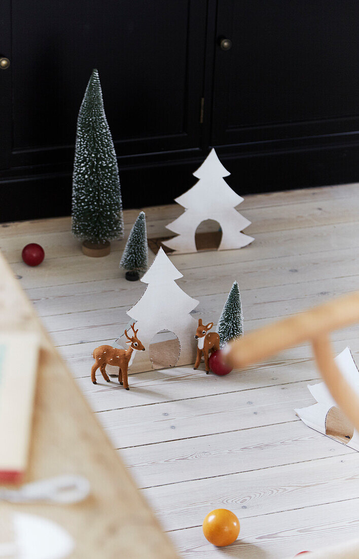 Weihnachtliche Dekoration mit Tannenbäumen und Rehen im Miniaturformat