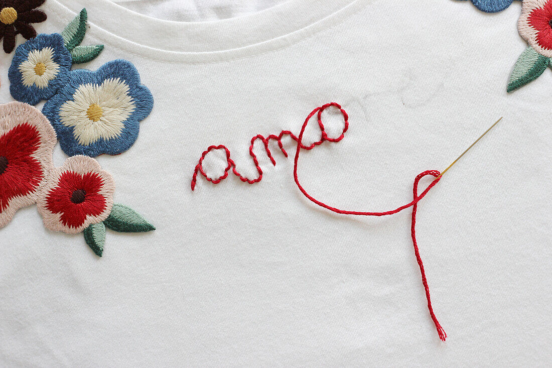 Stickerei mit Blüten und Schriftzug 'amore'