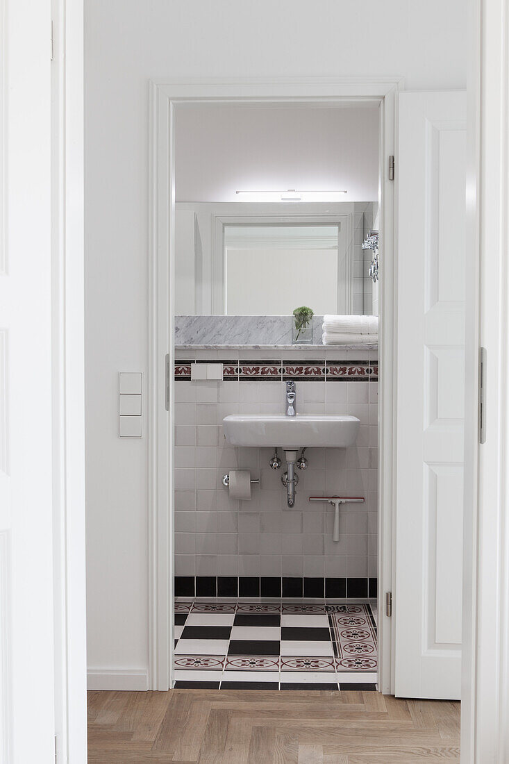 View of washbasin and mirror in bathroom through open door