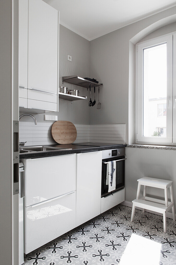 Unterschrank mit Glanzfront und Zementfliesen in kleiner Küche