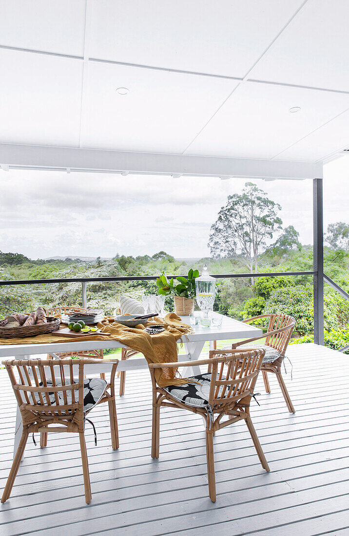 Esstisch mit Stühlen auf überdachter Terrasse mit Landschaftsblick