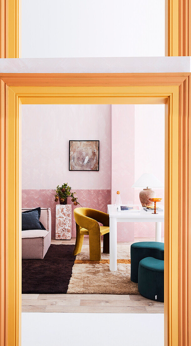 White dining table and various seating furniture in a room with a pink wall