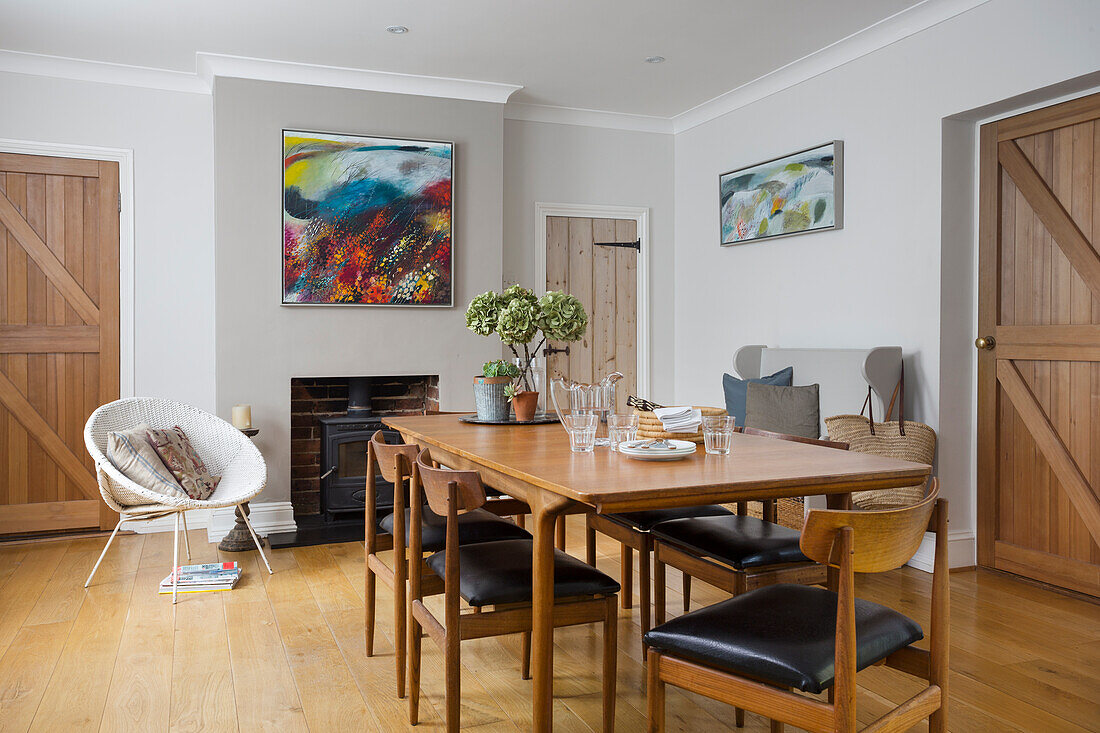 Dining area with vintage furniture, modern art above wood-burning stove