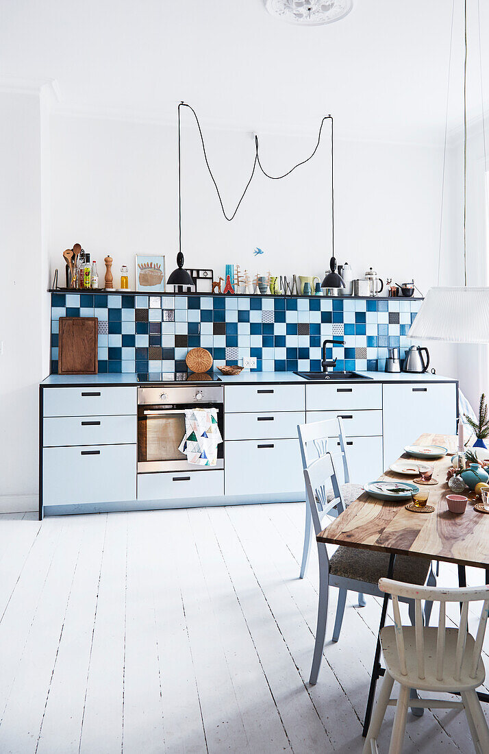 Light kitchenette, graphic tiled wall above, dining area in the foreground