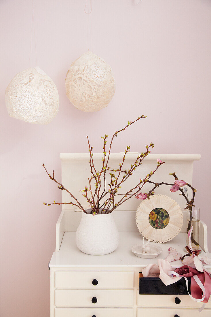 Vase mit treibenden Zweigen von Zierkirsche und Magnolie