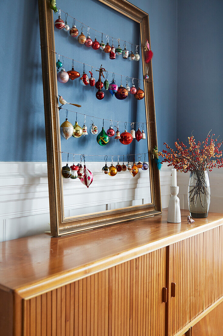Alter Bilderrahmen mit Vintage-Weihnachtskugeln auf Sideboard