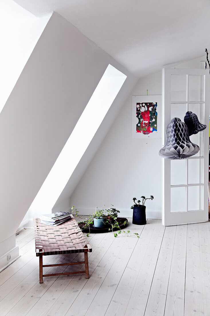 Hell gestaltetes Dachgeschoss mit Liegestuhl und Zimmerpflanzen
