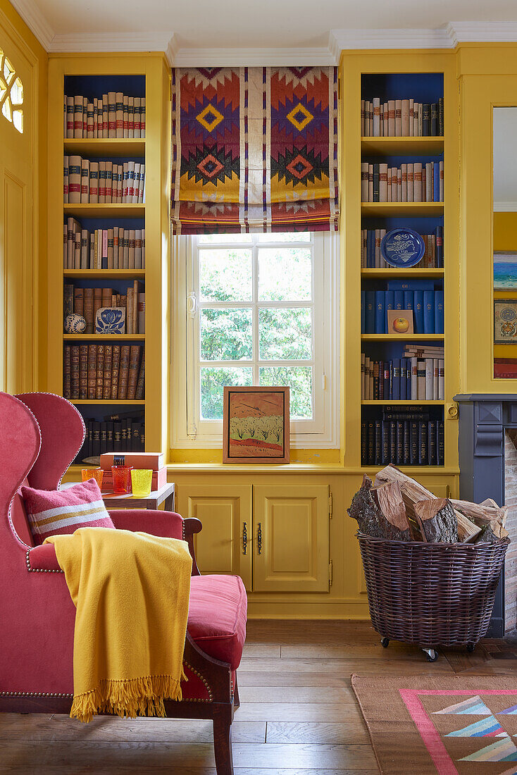 Yellow bookcase and pink armchairs in the living room of a French country house