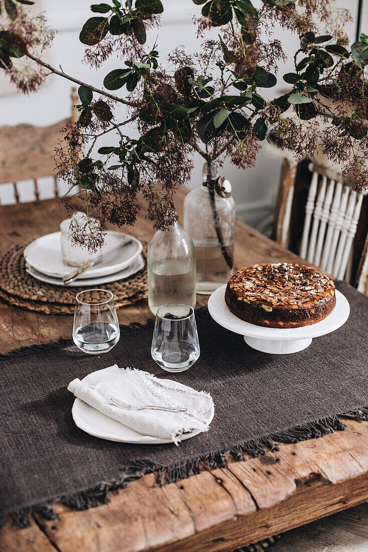 Rustikal gedeckter Holztisch mit Tischläufer und Kuchen