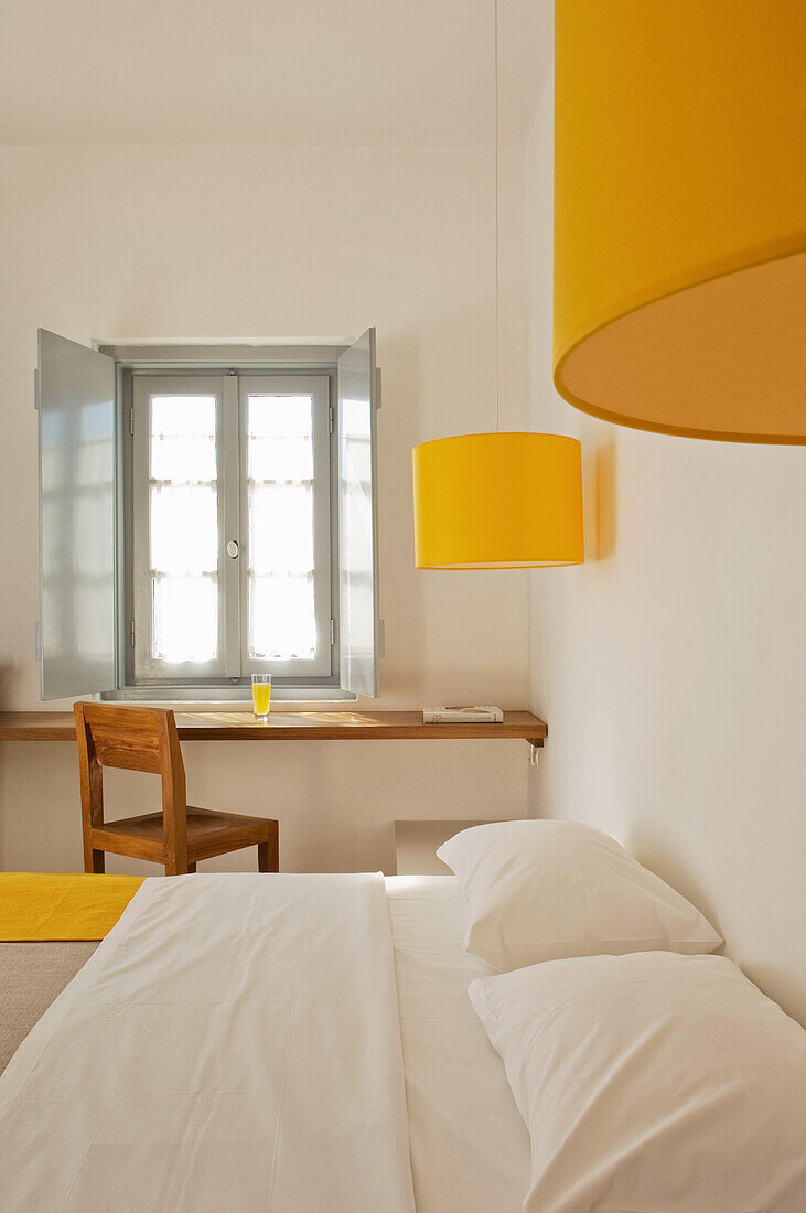 Queen bed and table in front of desk in bedroom with yellow accents