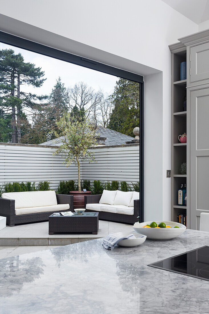Blick über Kücheninsel mit Marmoroberfläche auf elegante Terrasse