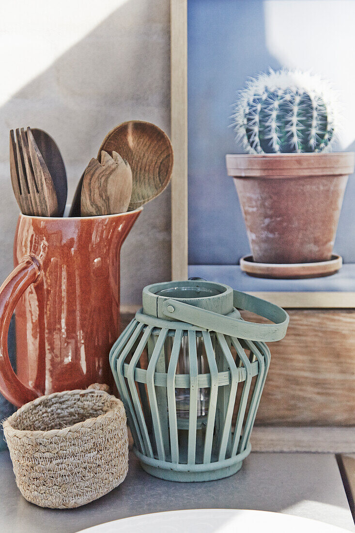 Laterne, Körbchen, Keramikkrug mit Kochlöffeln und Kaktus