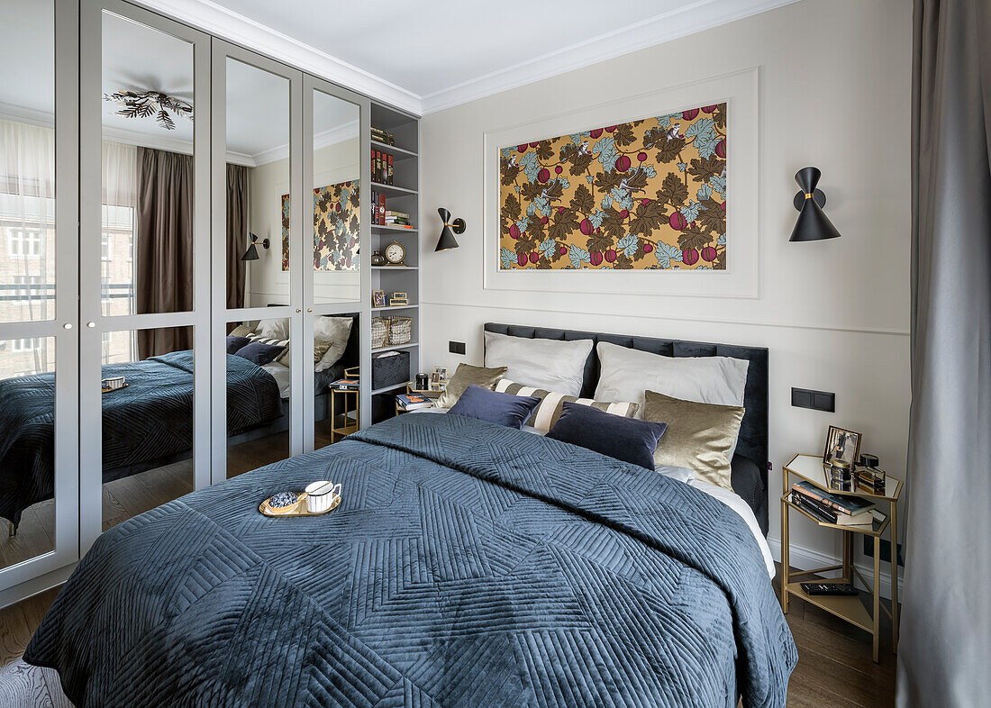 Doppelbett mit blauer Tagesdecke und Einbauschrank mit Spiegeltüren im Schlafzimmer