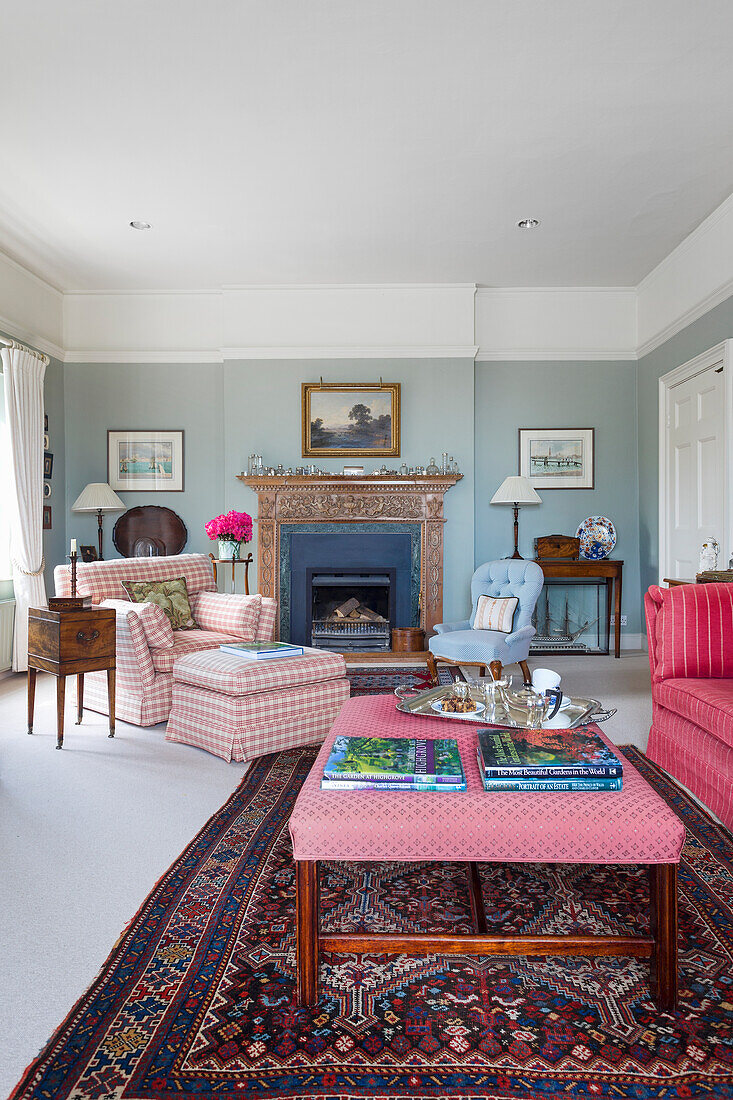 Upholstered furniture, antiques and fireplace in living room with blue walls