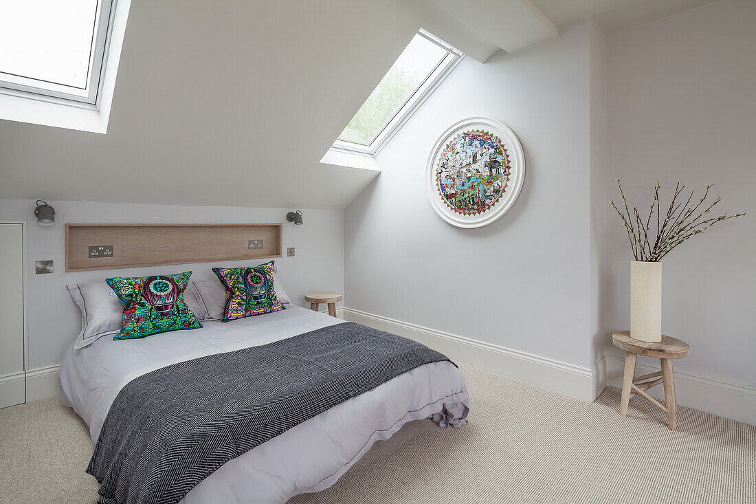 Double bed below wood-panelled wall niche in bright bedroom with skylight