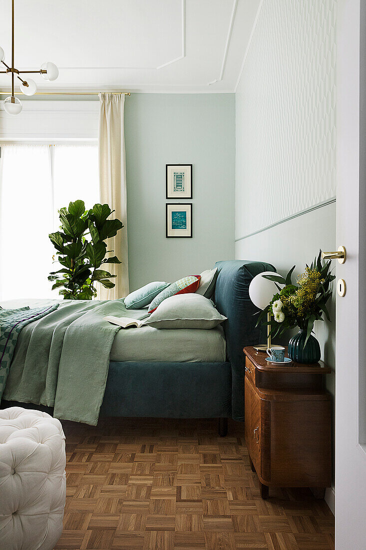 Doppelbett in blau-grünen Tönen und Zimmerpflanzen im Schlafzimmer