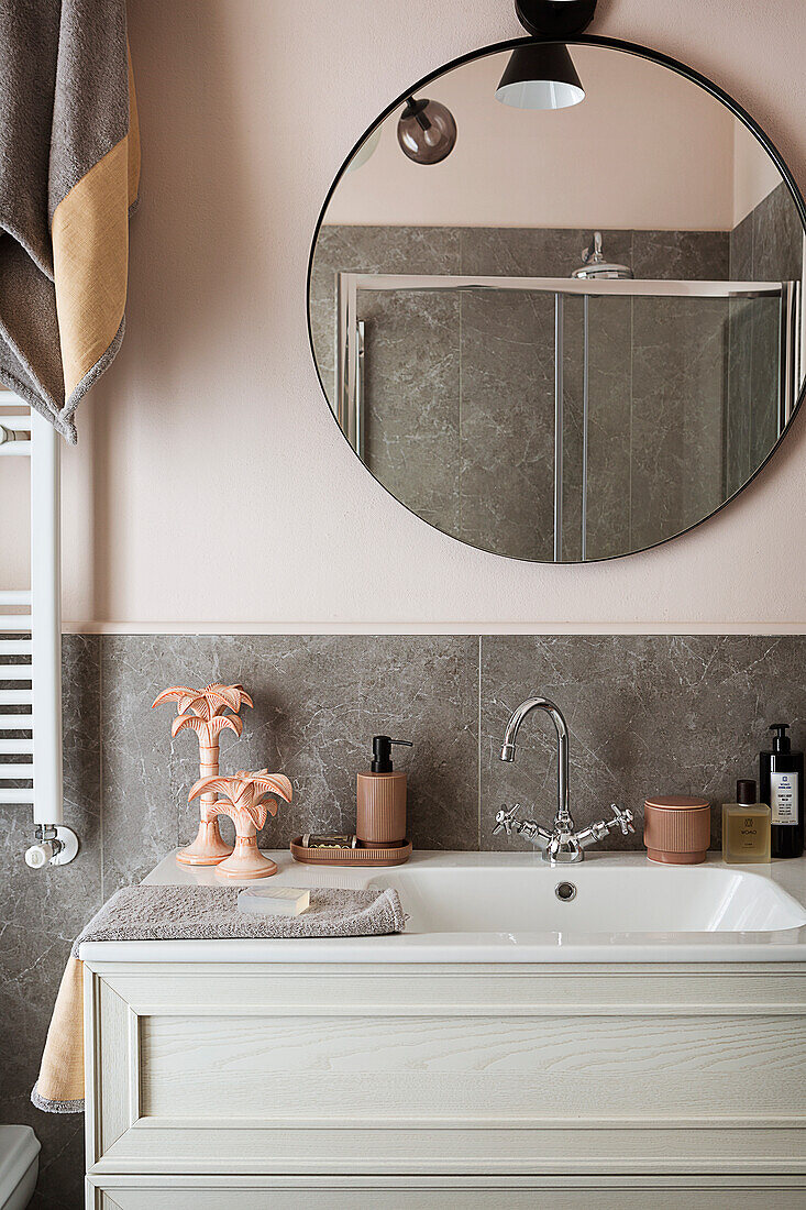 White washbasin and mirror in bathroom with pink walls and grey tiles
