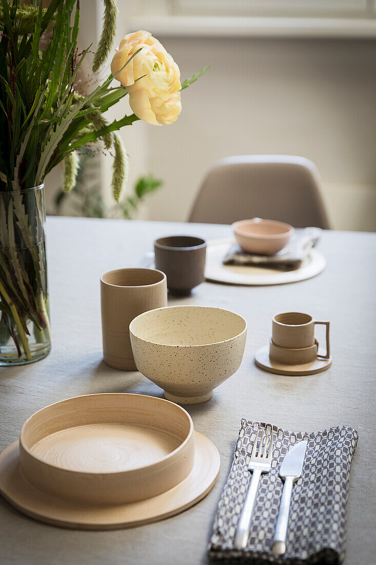 Gedeckter Tisch mit Leinendecke und Keramikgeschirr in Naturtönen