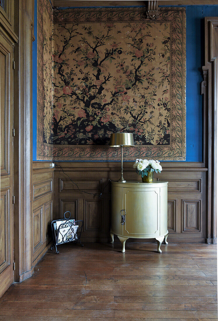 Anitkes Schränkchen im Raum mit großformatigem Wandteppich und Holzverkleidung