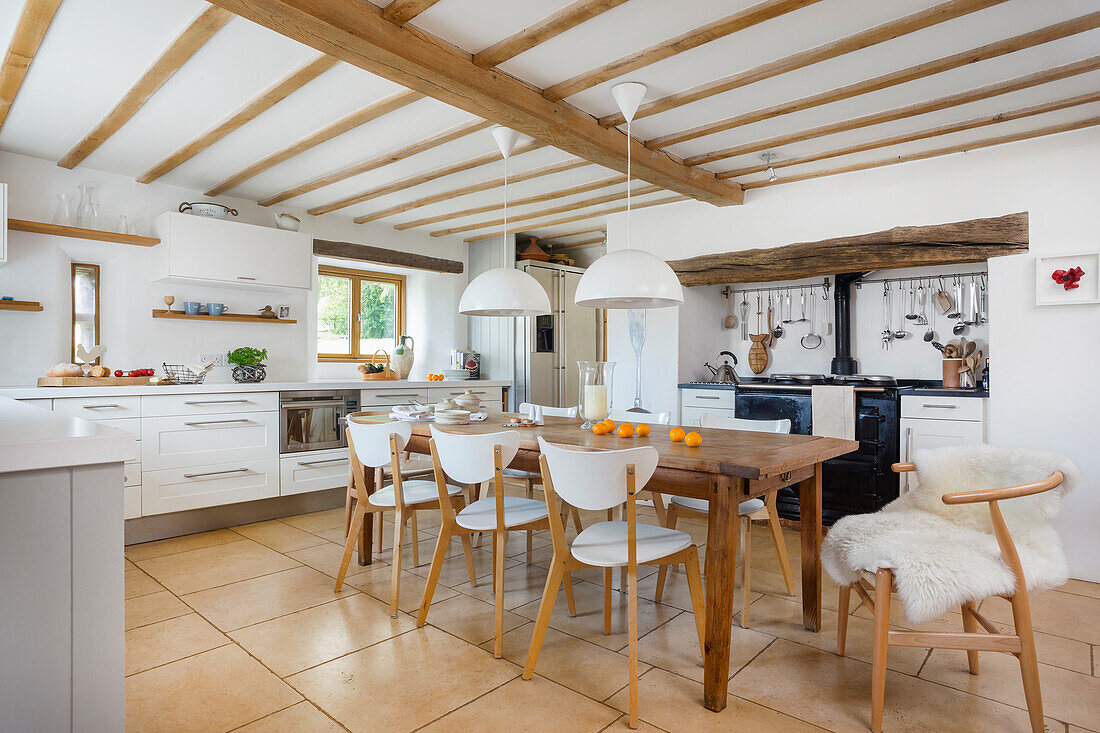 Weiße Wohnküche mit Esstisch aus Holz in umgebauter Scheune