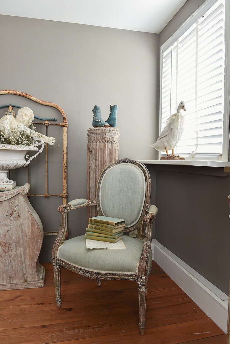 Antique upholstered chair and vintage-style decorations against grey wall