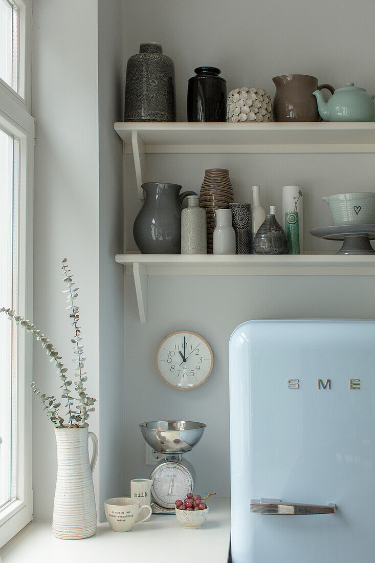 Regal mit Keramiksammlung über Kühlschrank in der Küche