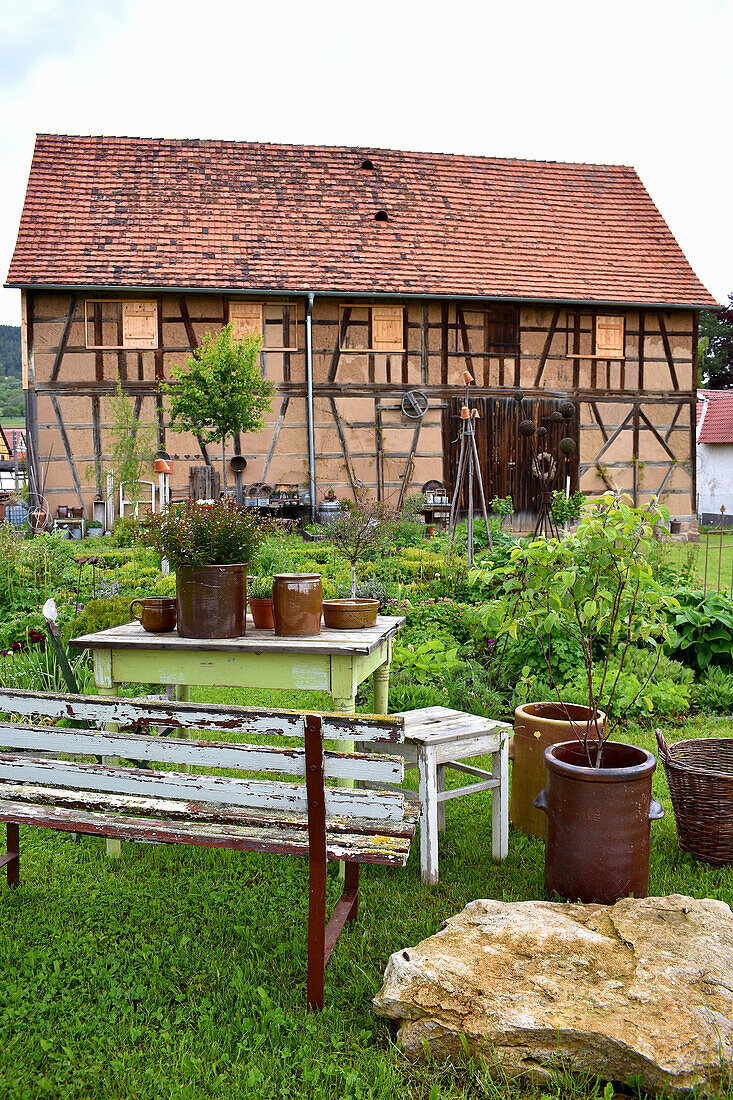 Rustic seating area with stoneware pots and view of the cottage garden and barn