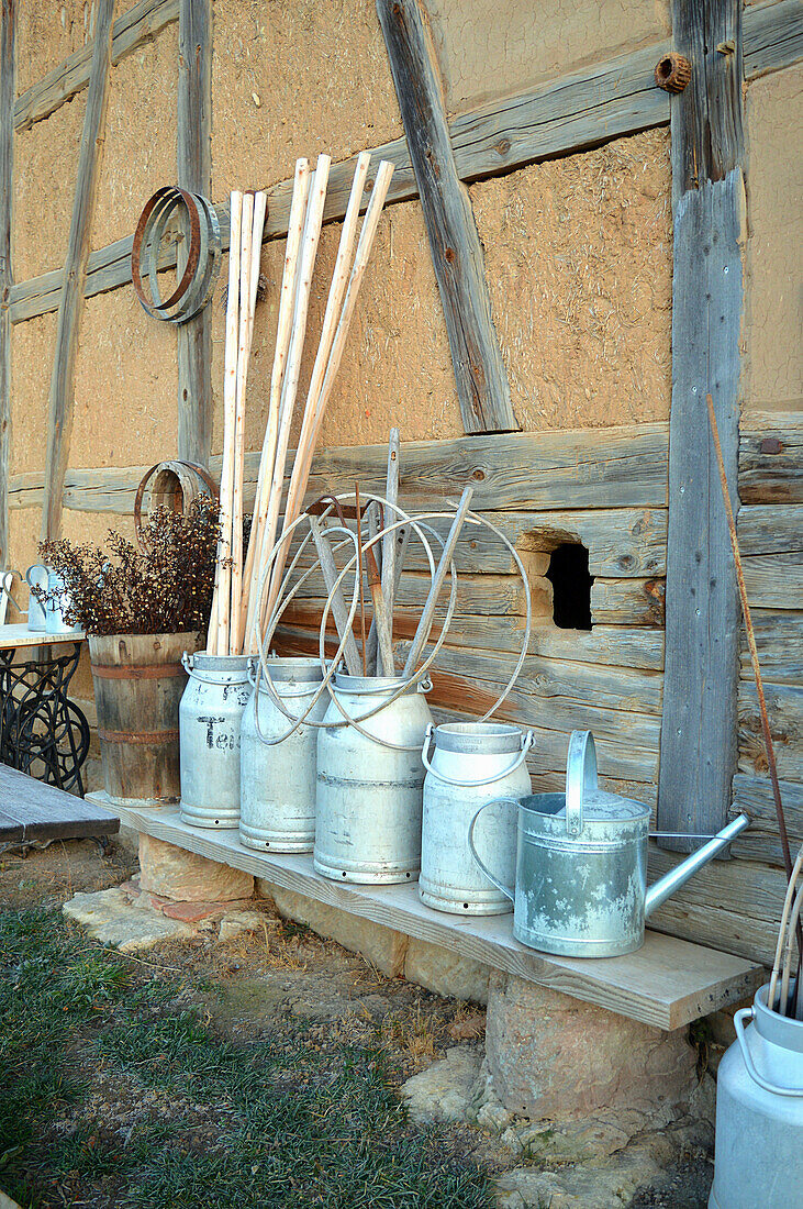 Old milk churns against a barn wall