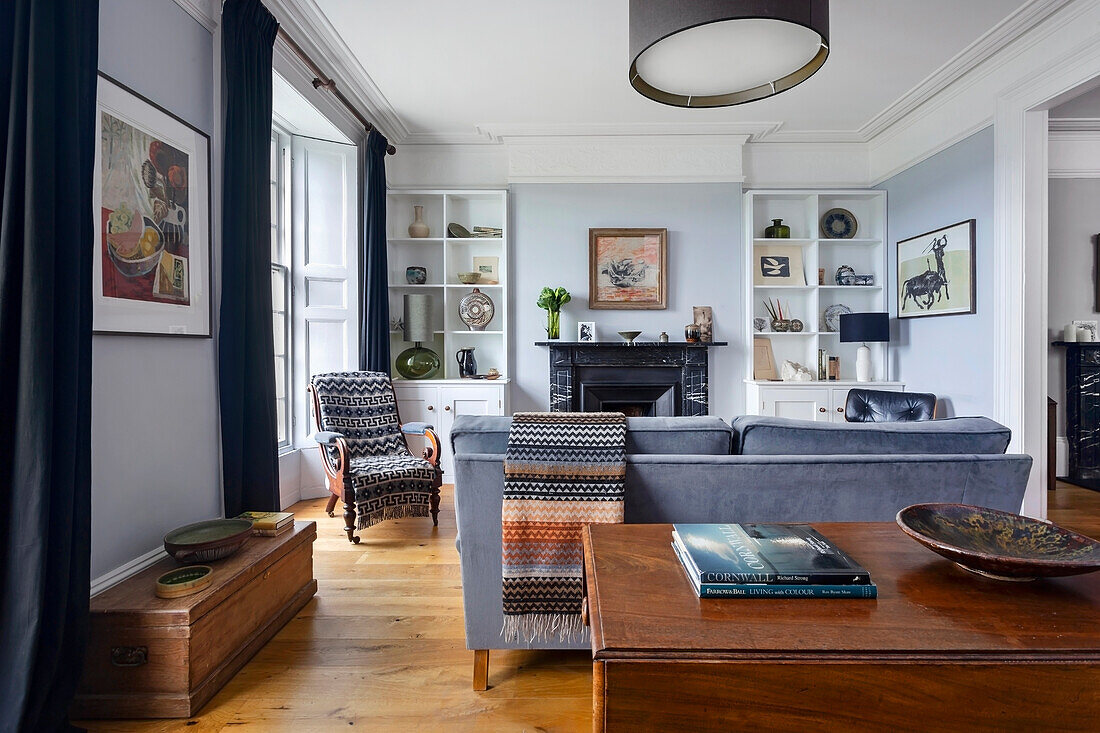 Wooden table and small oak chest, behind it seating area with grey sofa in the living room