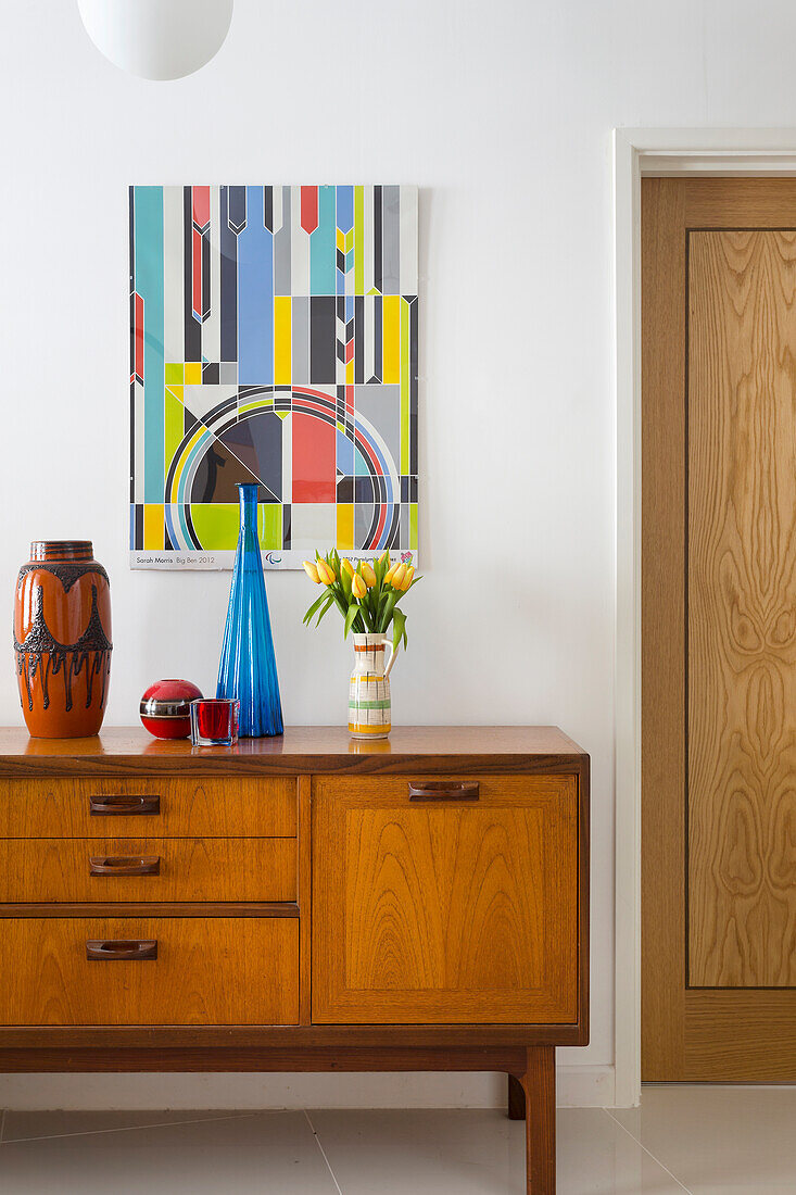 60s sideboard with vases, above it modern art in the hallway