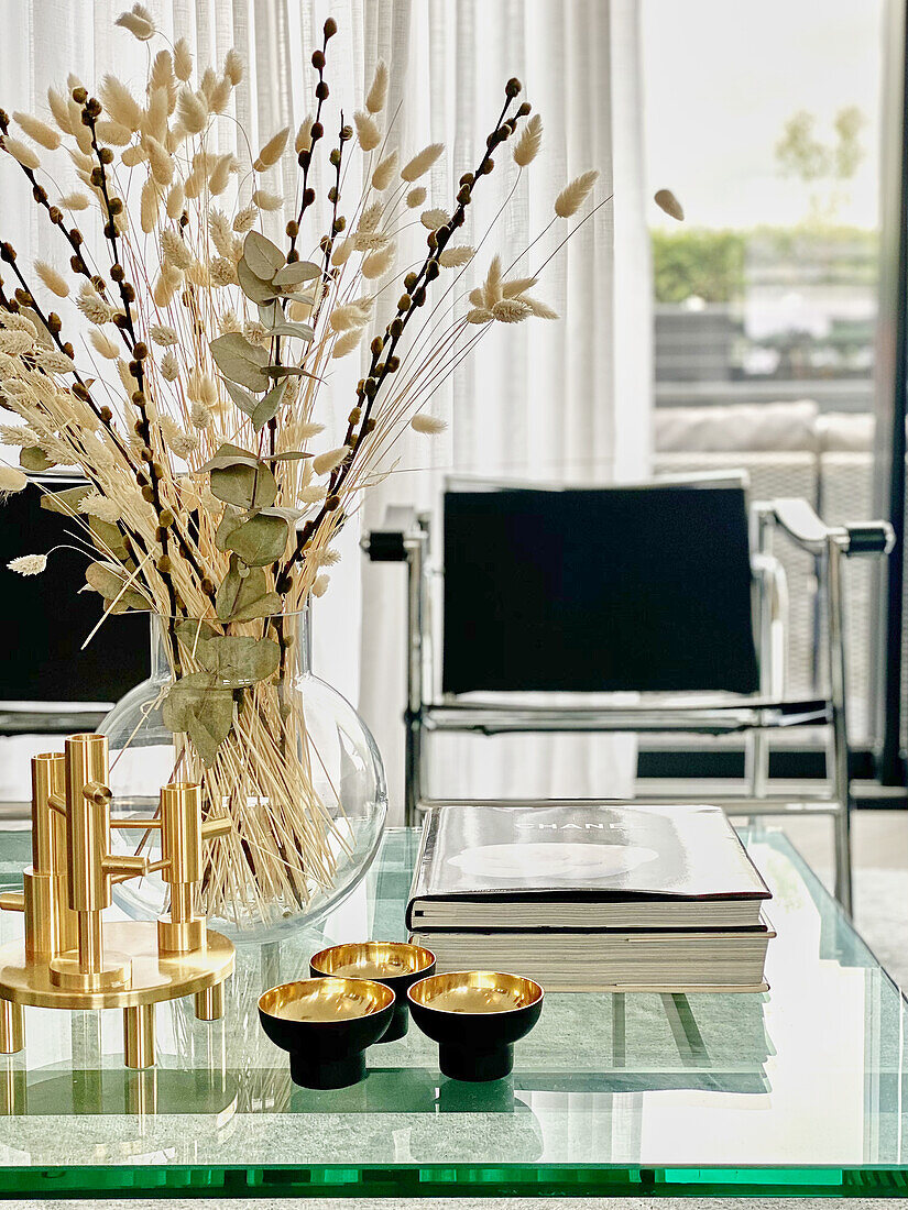 Blick über Glastisch mit Vase auf verchromten Stuhl vor Terrassentür