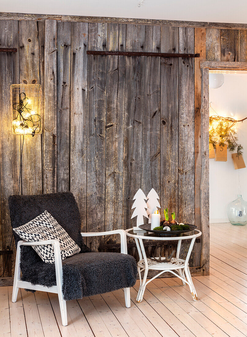 Sessel mit Kissen, Beistelltisch, rustikale Holzwand und Weihnachtsdekoration