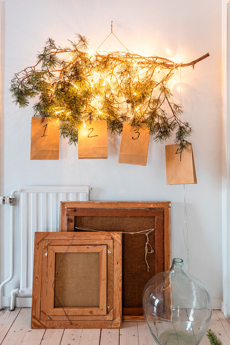 Illuminated Advent calendar made from a branch with twigs and paper bags with numbers