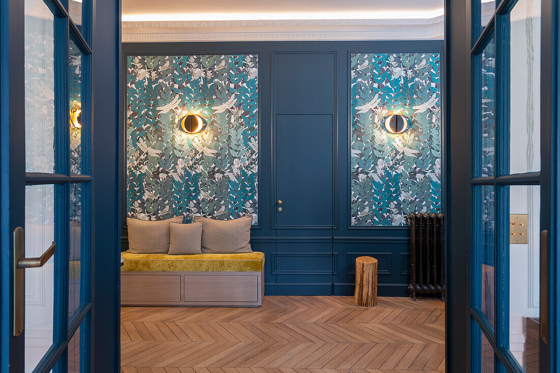 Wallpaper with nature motif and bench in the living area with herringbone parquet flooring