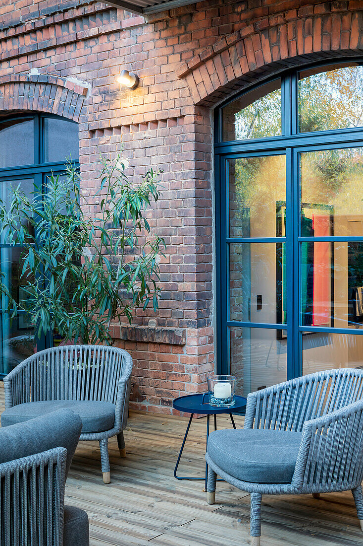 Terrace with armchairs and bamboo plant in front of brick wall