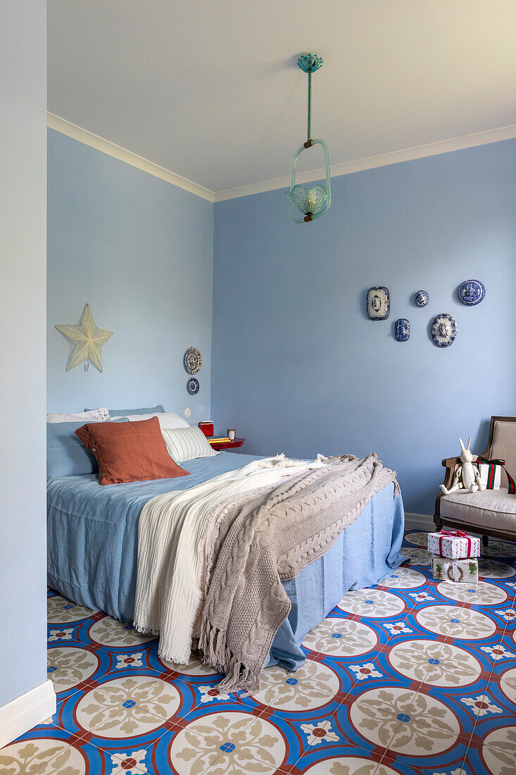 Bedroom with light blue walls, patterned tiled floor and wall decoration