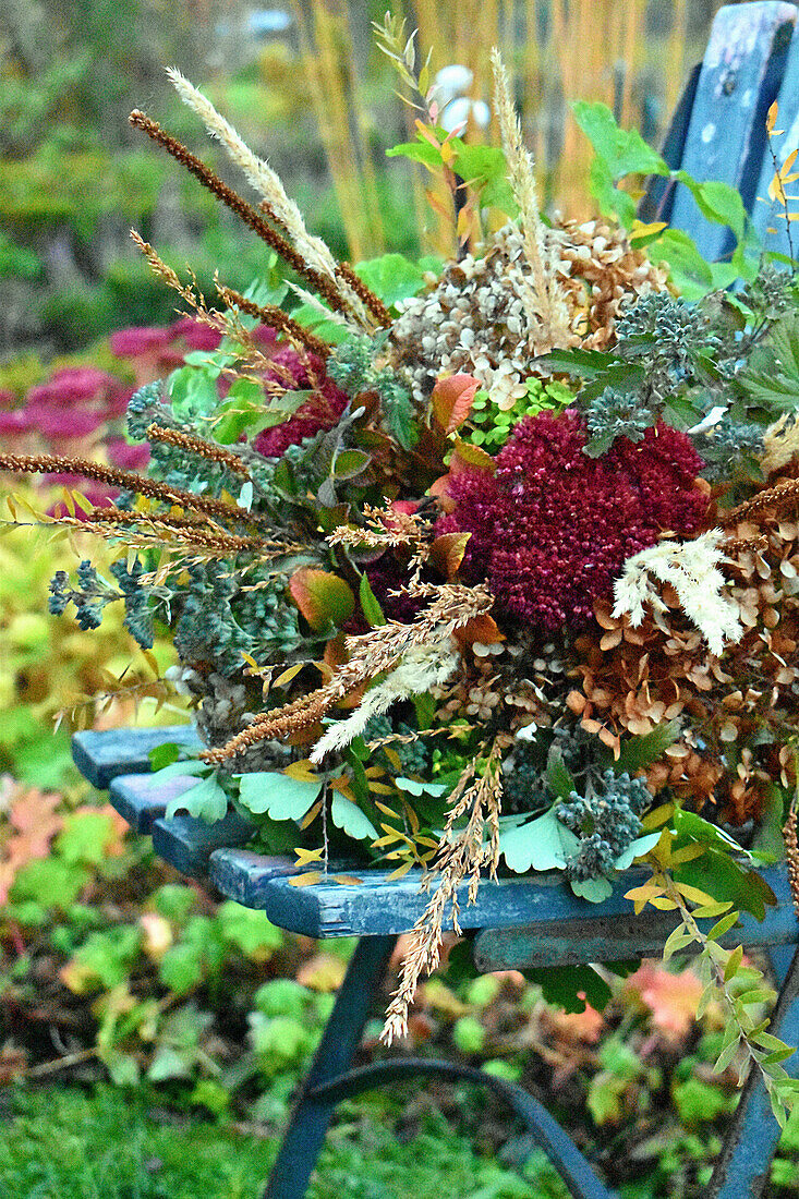 Herbstlicher Blumenstrauß auf Gartenstuhl