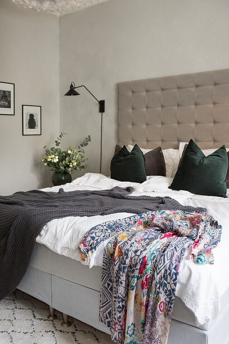 Bett mit gepolstertem Kopfteil, Decken und Kissen im Schlafzimmer