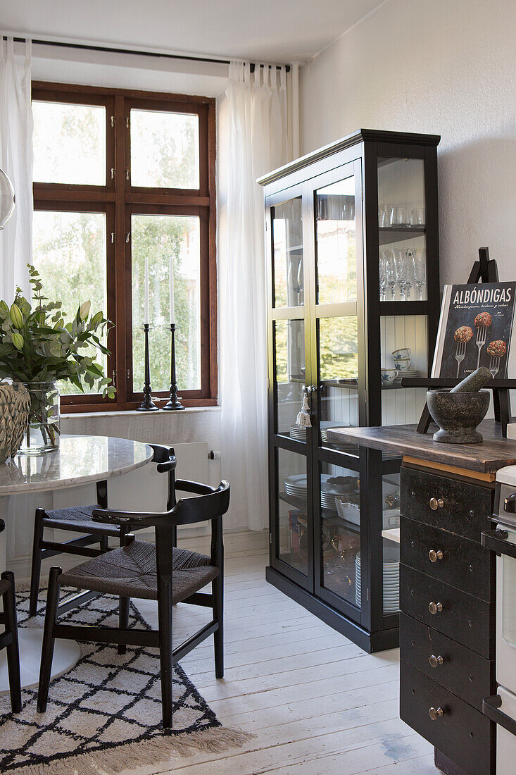 Black display cabinet next to window, dining table and chairs