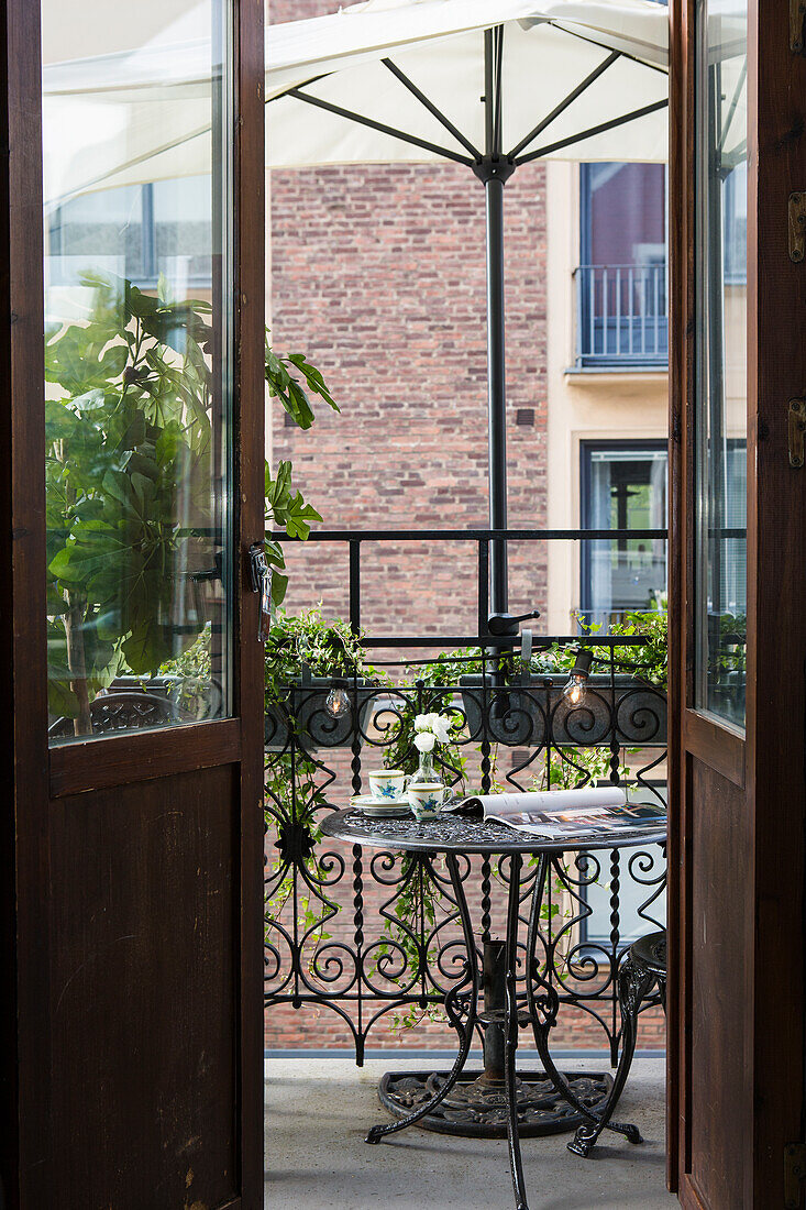 Blick auf kleinen Balkon mit schmiedeeisernem Tisch und Pflanzen