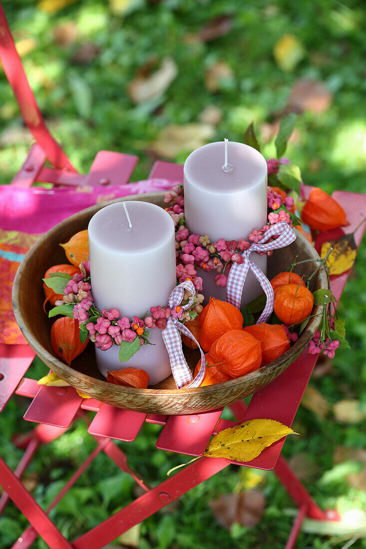 Kerzen mit Pfaffenhütchen und Lampionblumen in einer Schale