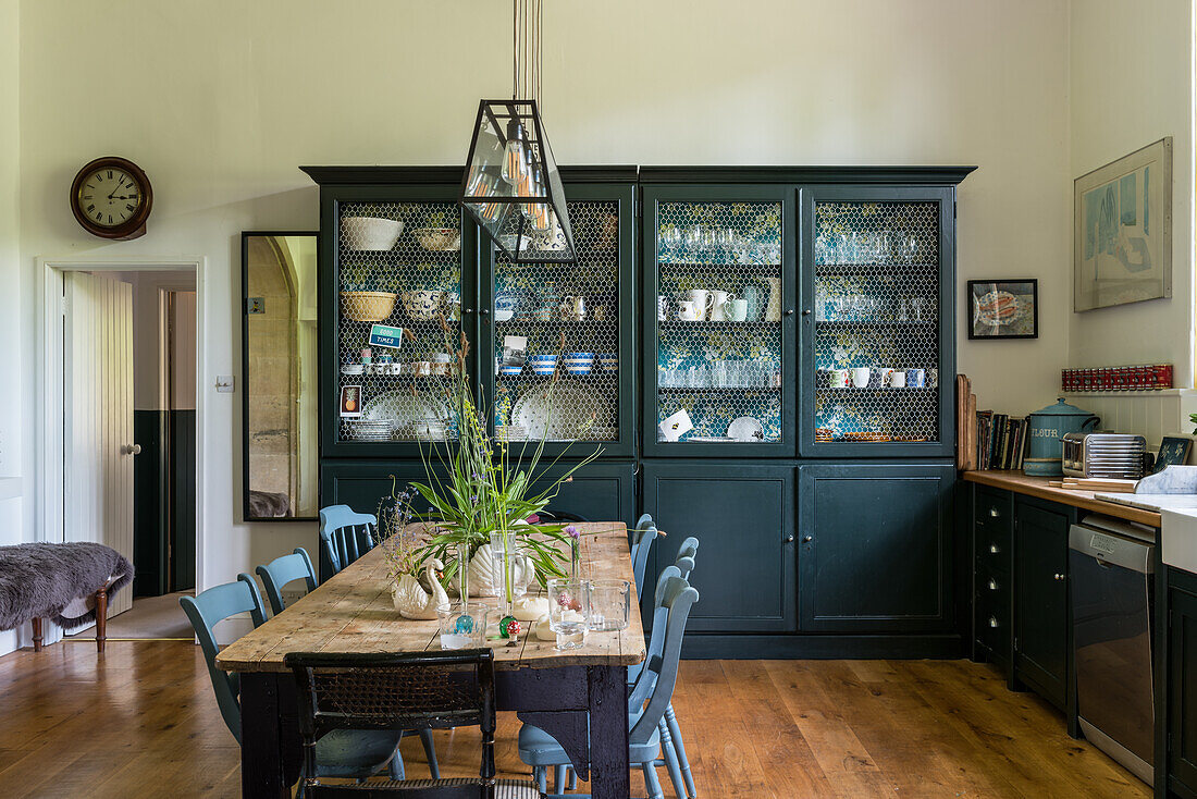 Esszimmer mit rustikalem Holztisch und schwarzer Vitrine