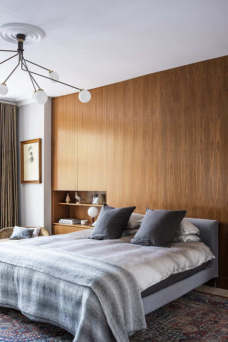 Minimalist bedroom with wooden paneled wall and modern pendant light