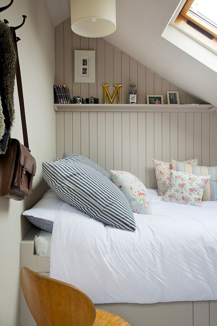 Bed under a sloping ceiling with a skylight and wall paneling