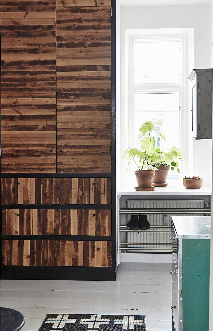 Garderobenschrank im Patchwork-Holzdesign und Zimmerpflanzen auf Fensterbank