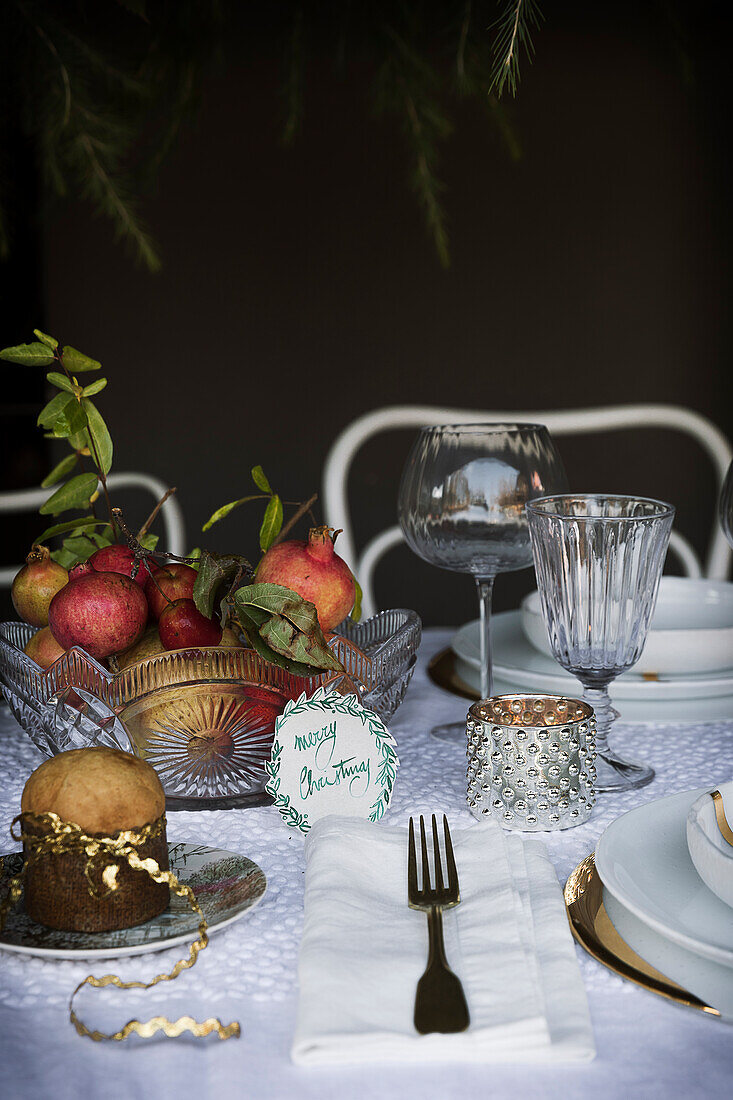 Christmas table festively set with white tablecloth and fruit basket