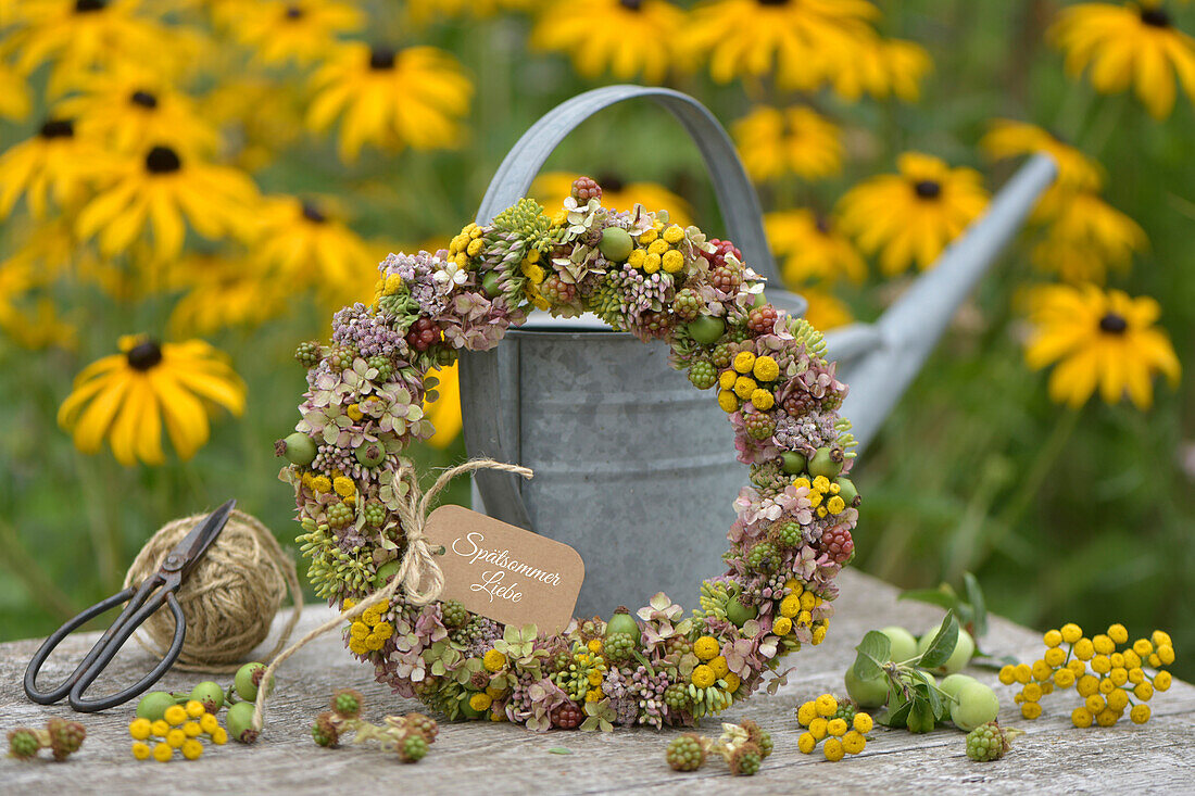 Late summer wreath made of sedum, tansy, blackberries, rose hips and hydrangeas on a wire ring