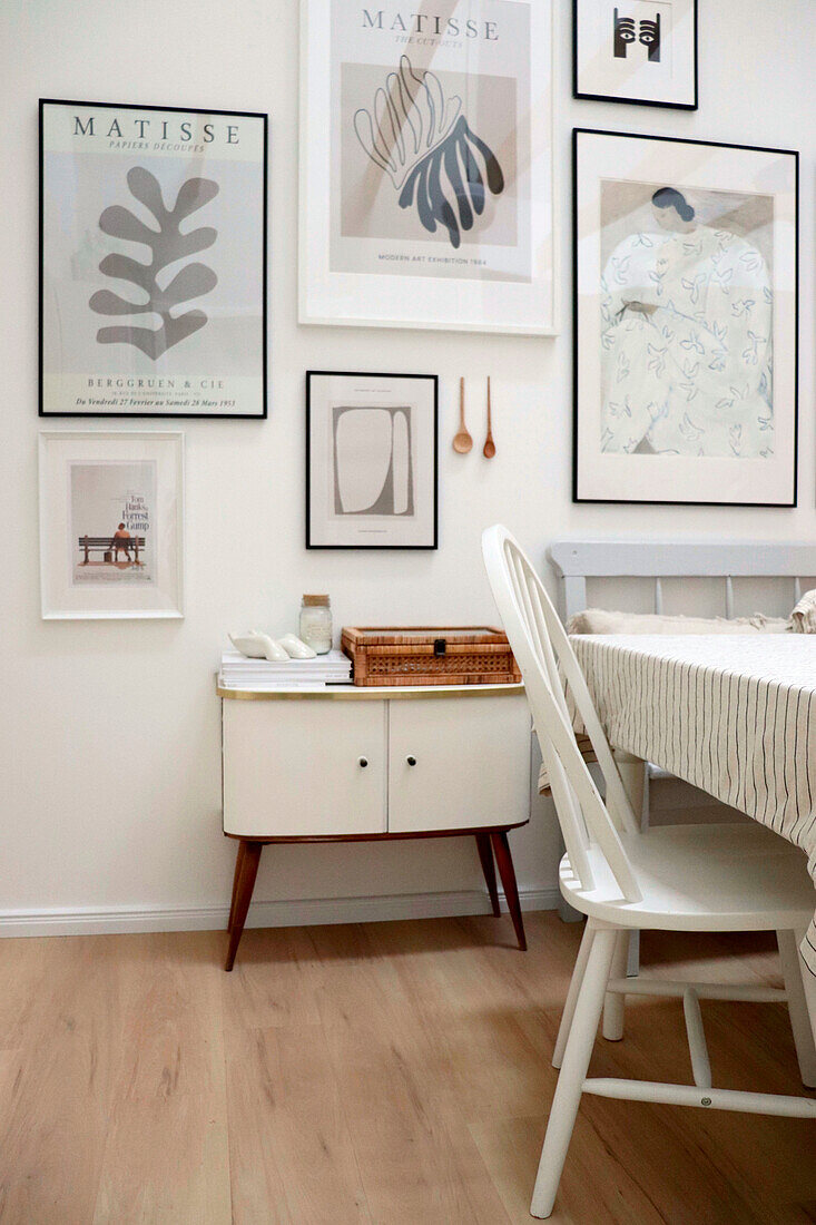 Dining area with white chair, vintage chest of drawers and framed artwork on the wall